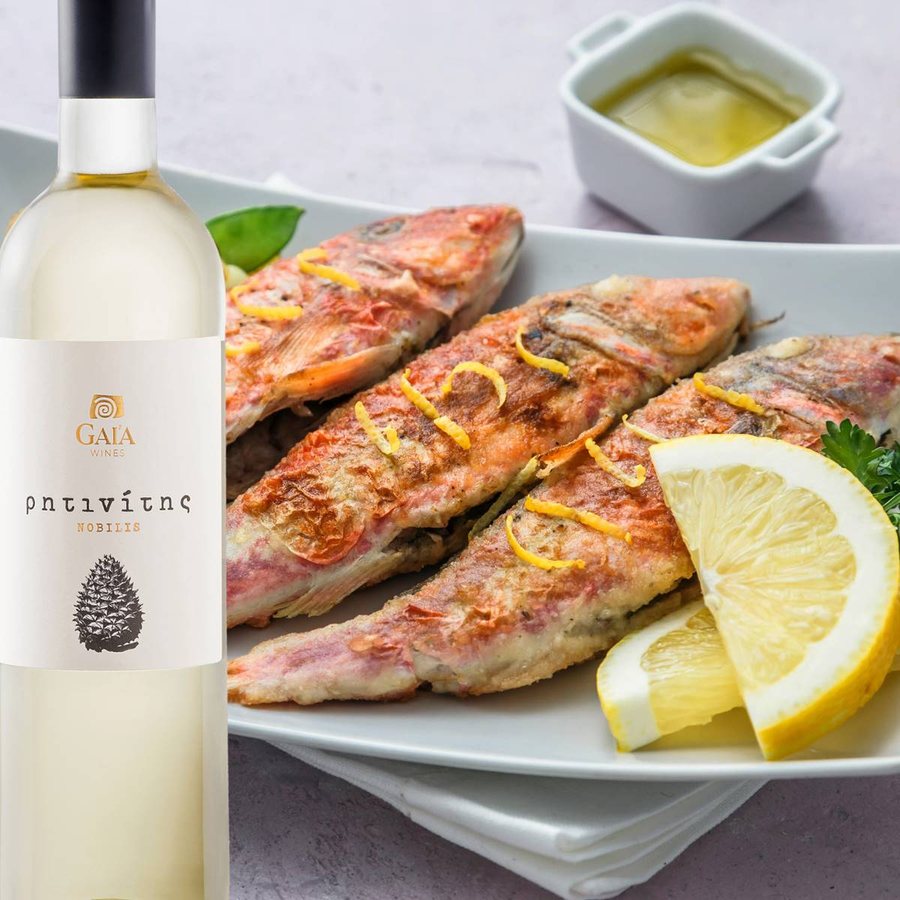 A bottle of Gaia Ritinitis Nobilis retsina beside a plate of fried red mullet with lemon