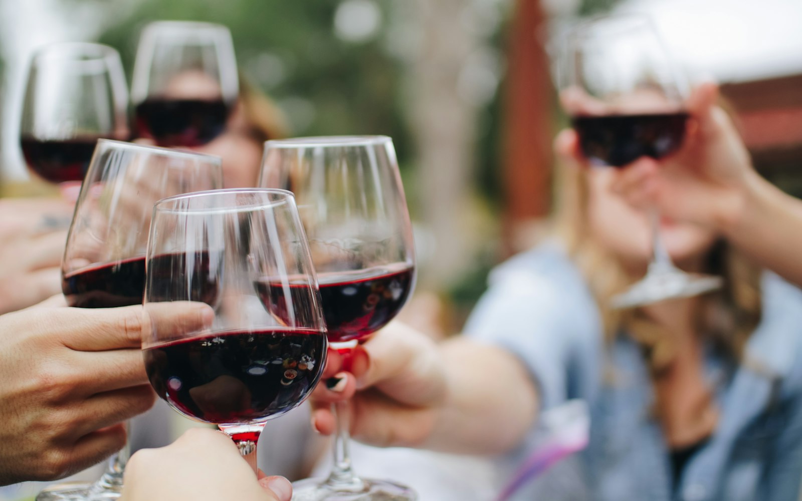 Two glasses of red wine being clinked in a toast